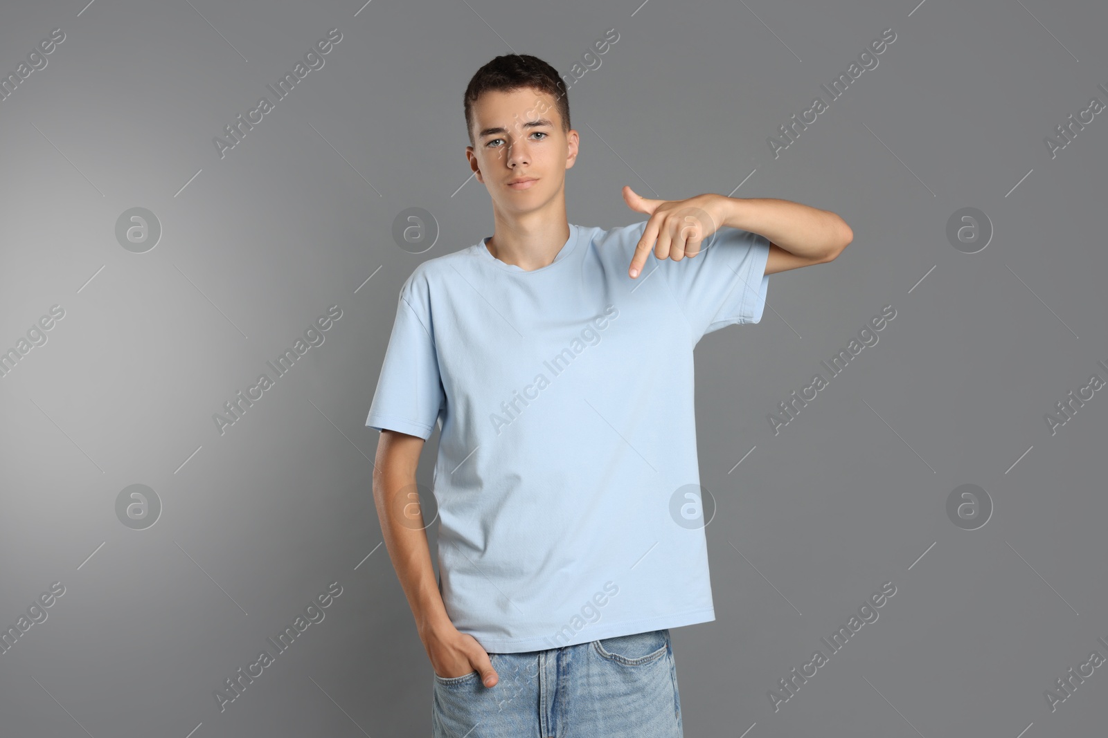 Photo of Teenage boy wearing light blue t-shirt on grey background