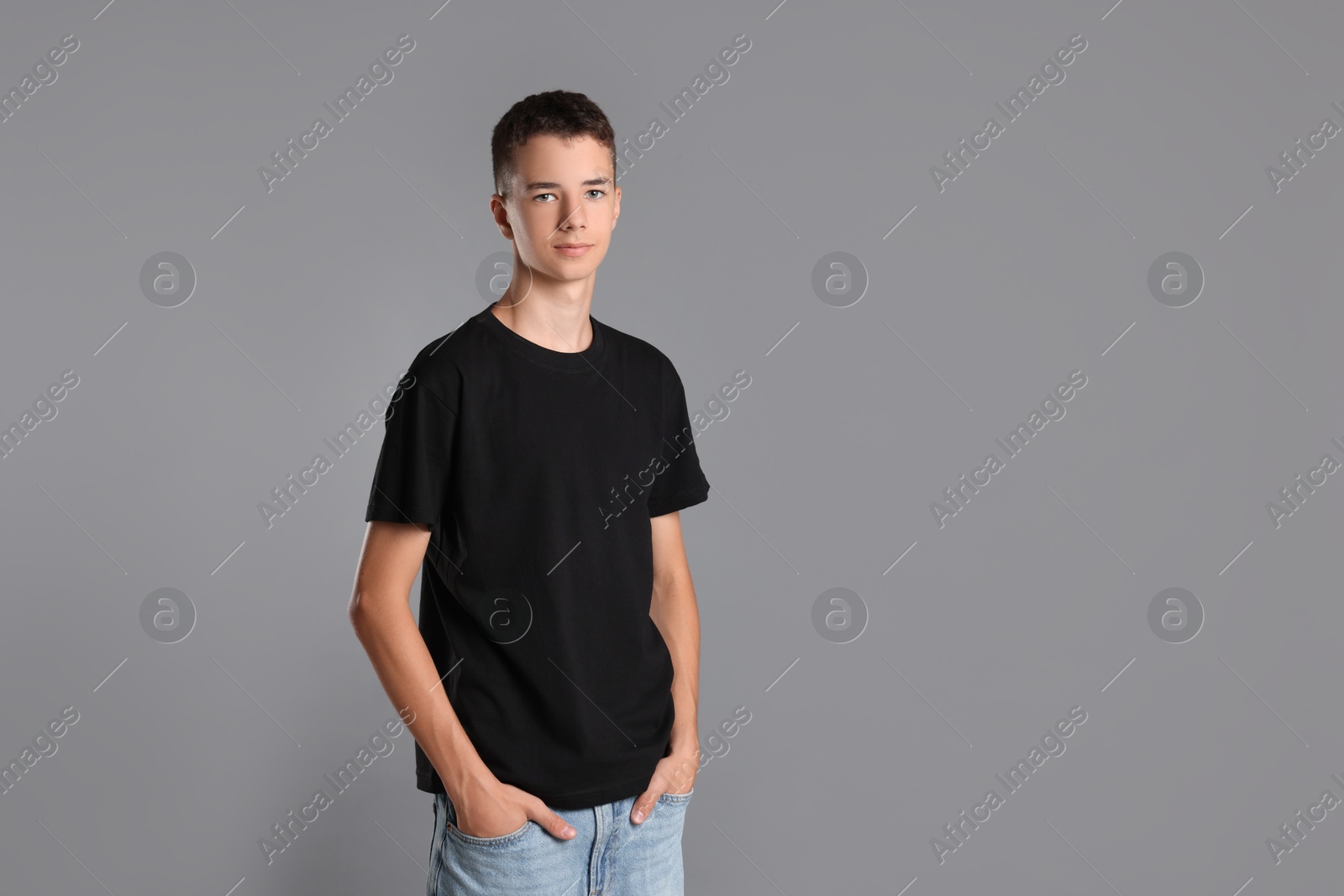 Photo of Teenage boy wearing black t-shirt on grey background, space for text