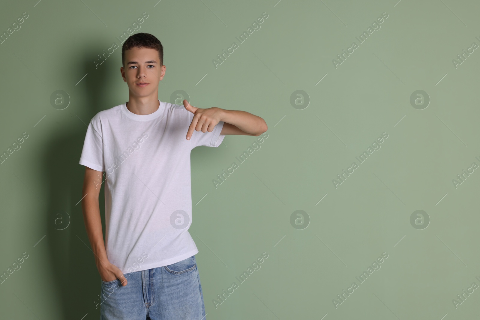 Photo of Teenage boy wearing white t-shirt on green background, space for text