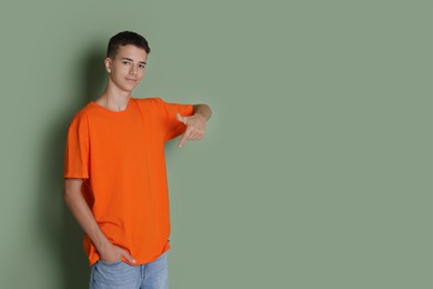 Photo of Teenage boy wearing orange t-shirt on green background, space for text