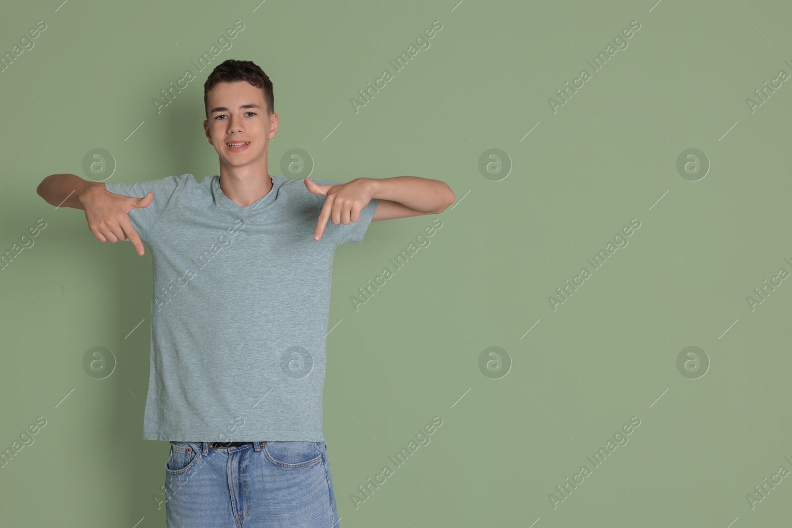 Photo of Teenage boy wearing light grey t-shirt on green background, space for text