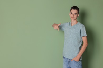 Teenage boy wearing light grey t-shirt on green background, space for text