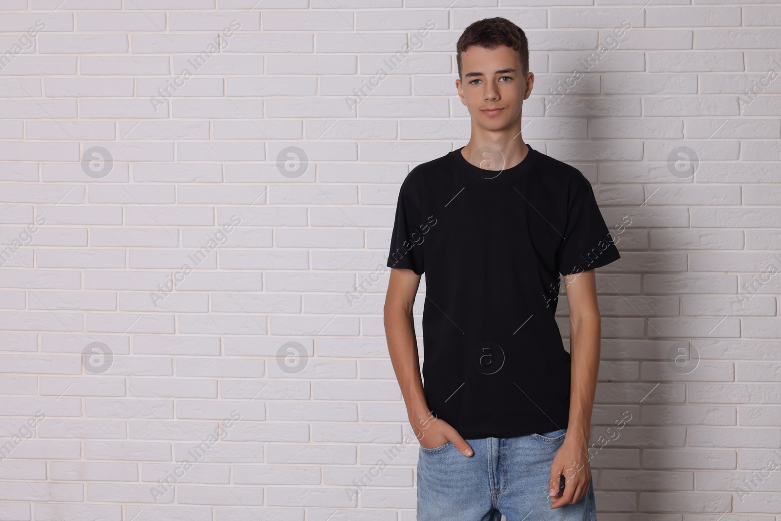 Photo of Teenage boy wearing black t-shirt near white brick wall, space for text