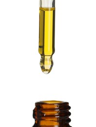 Photo of Dripping tincture from pipette into bottle on white background, closeup