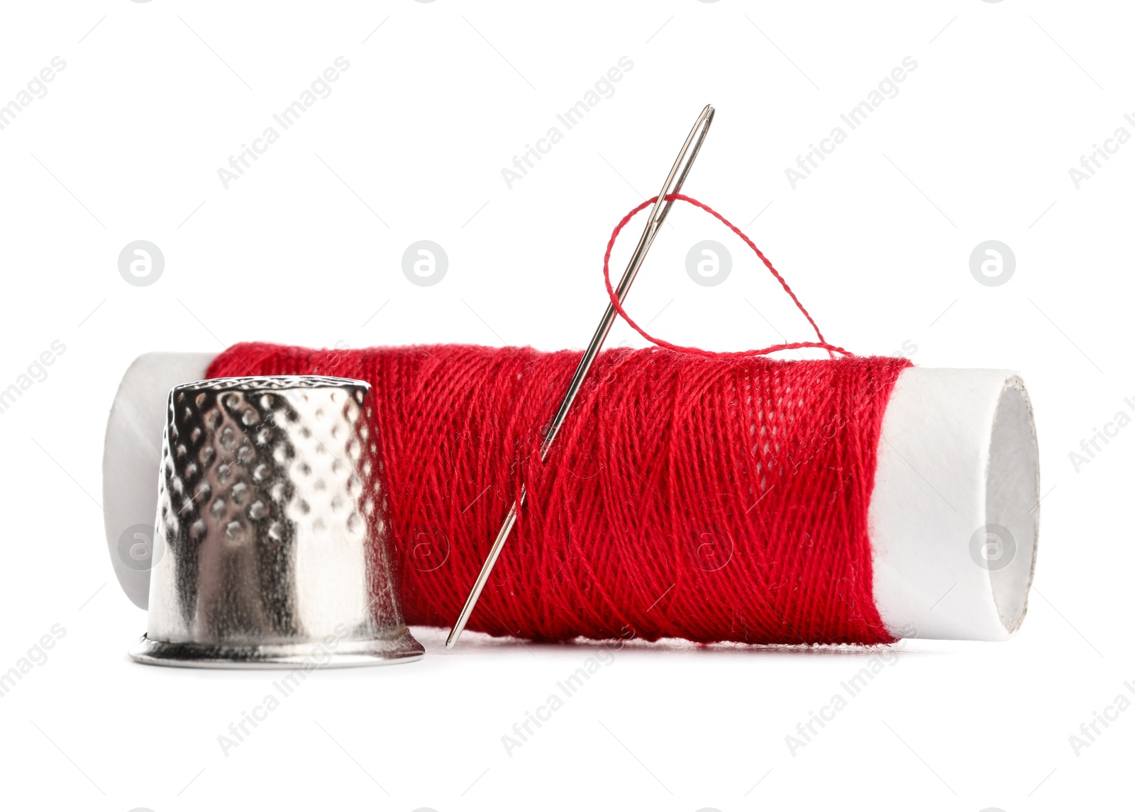 Photo of Thimble and needle with red sewing thread isolated on white