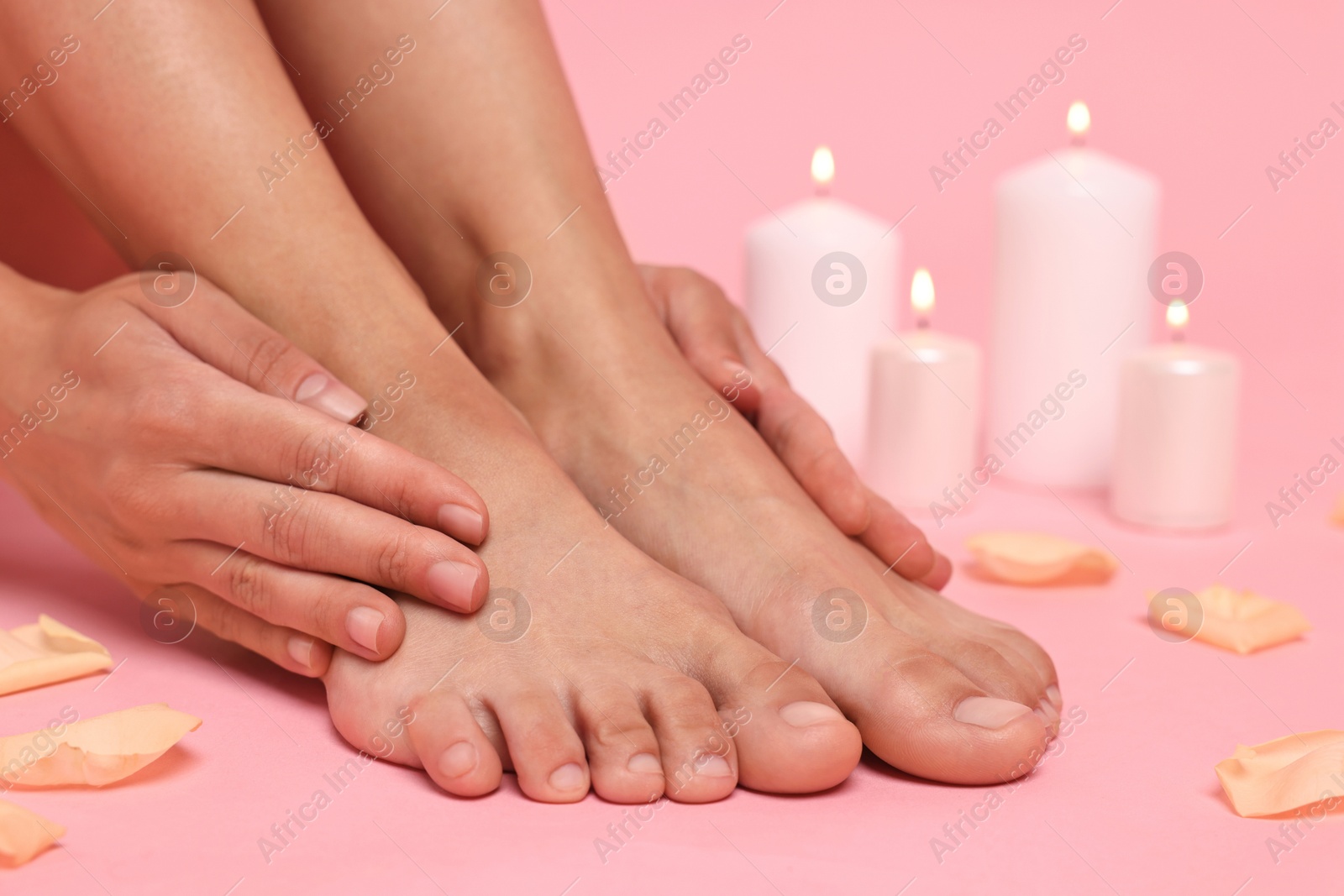 Photo of Woman touching her smooth feet on pink background, closeup