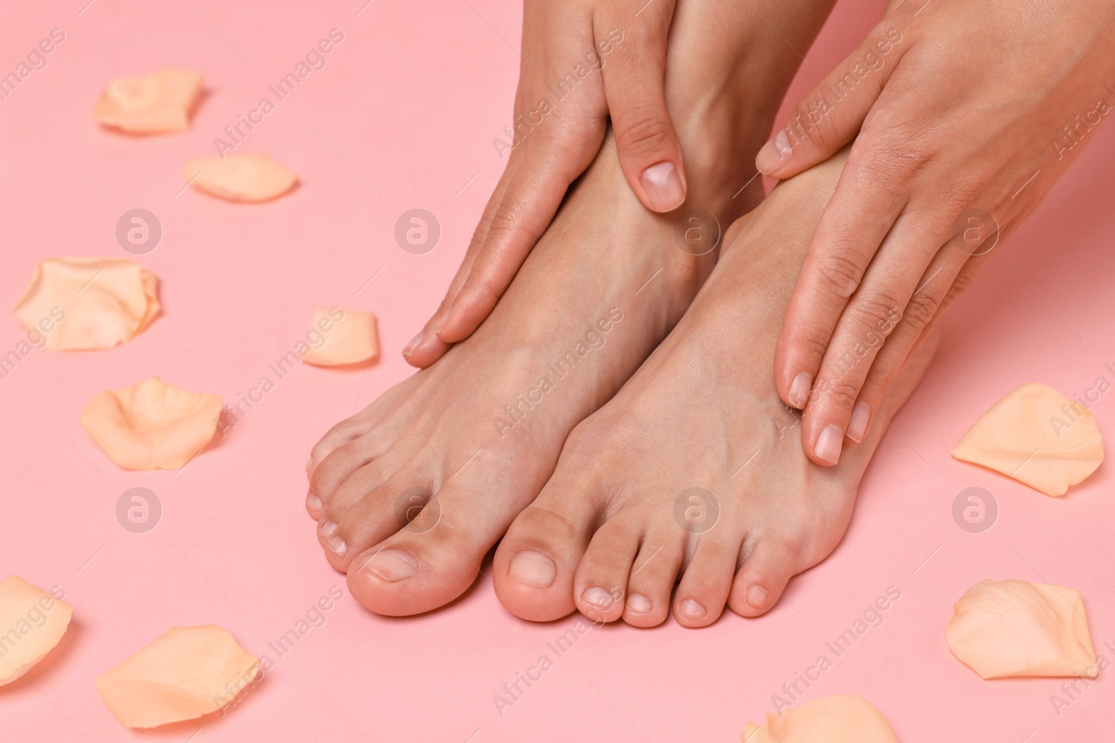 Photo of Woman touching her smooth feet on pink background, closeup