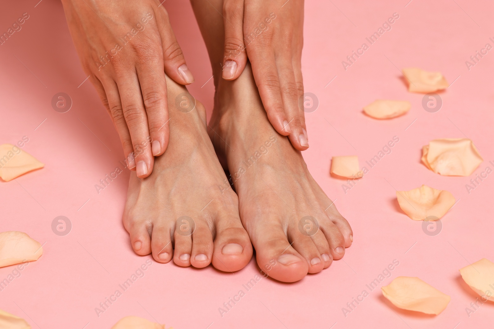 Photo of Woman touching her smooth feet on pink background, closeup