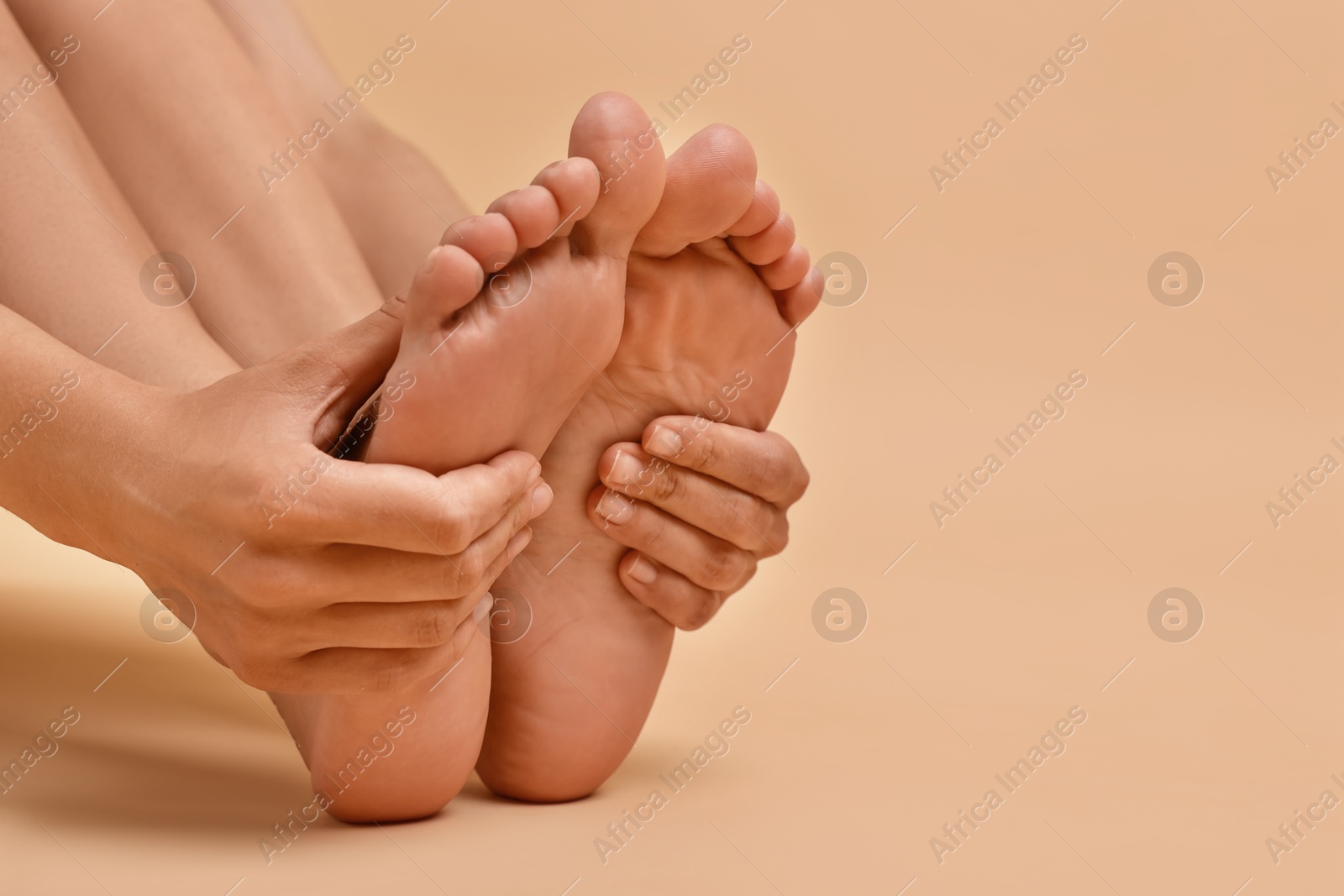 Photo of Woman touching her smooth feet on beige background, closeup. Space for text