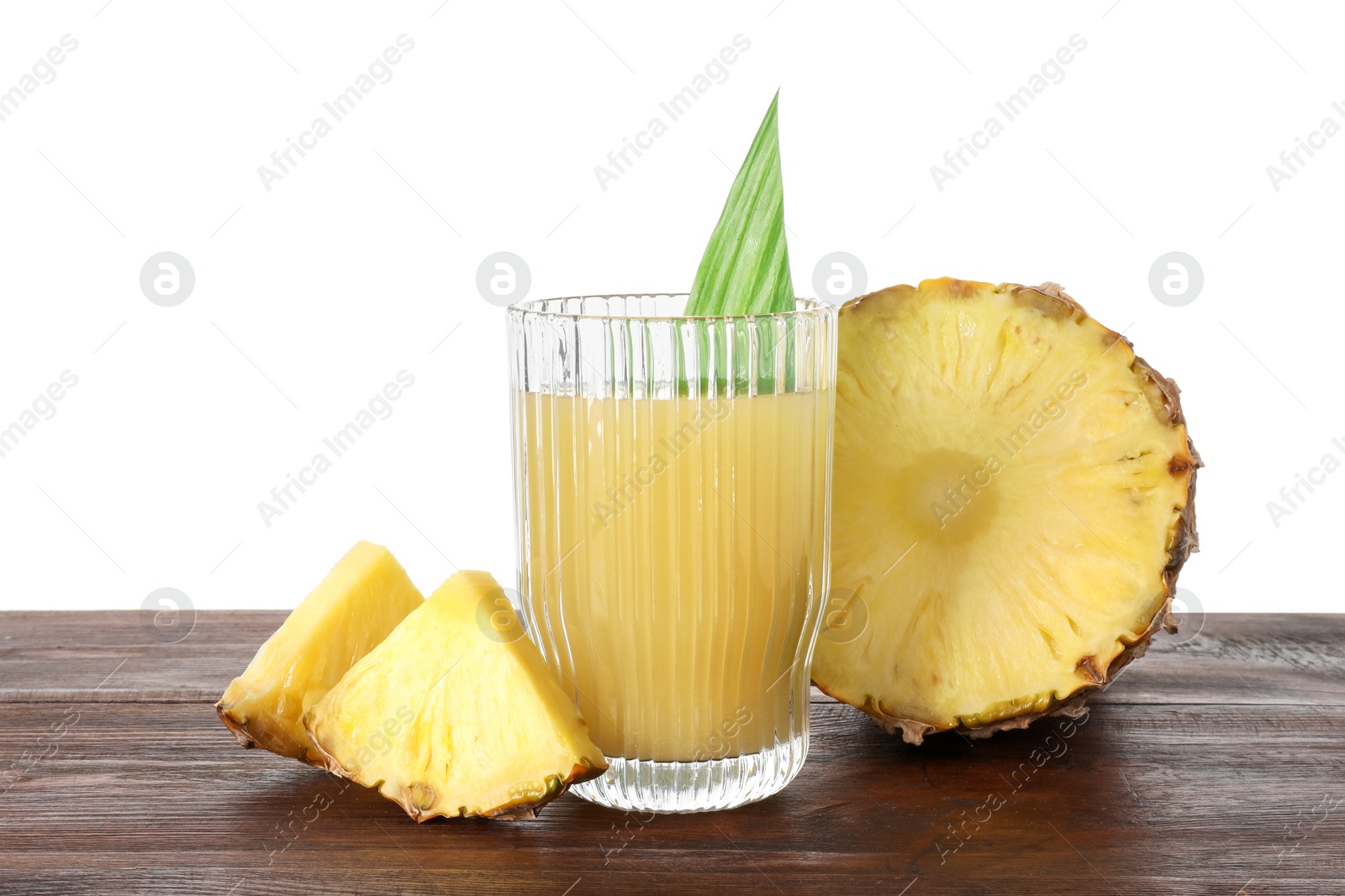 Photo of Glass with pineapple juice and pieces of fresh fruit on wooden table against white background