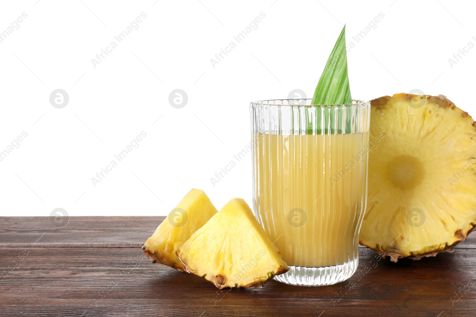 Photo of Glass with pineapple juice and pieces of fresh fruit on wooden table against white background