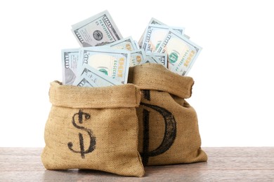 Photo of Dollar banknotes in bags on wooden table against white background