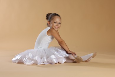 Portrait of little ballerina on beige background