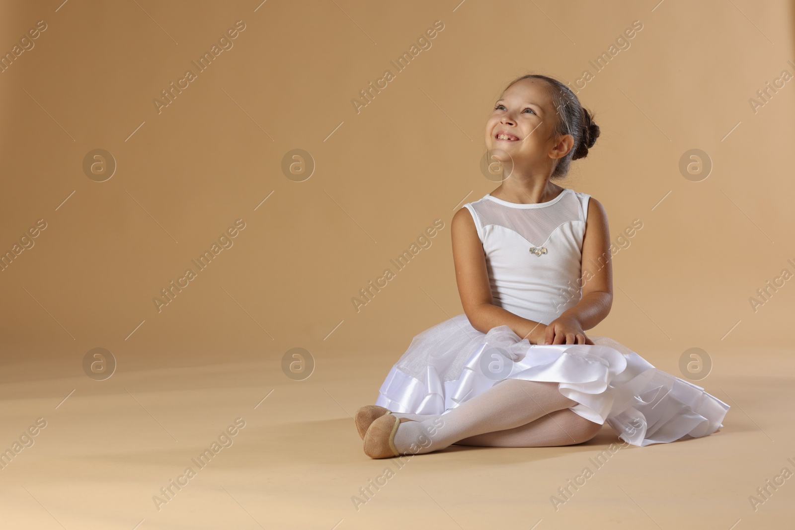 Photo of Portrait of little ballerina on beige background, space for text