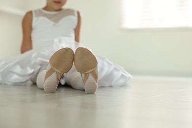 Little ballerina wearing pointe shoes indoors, closeup