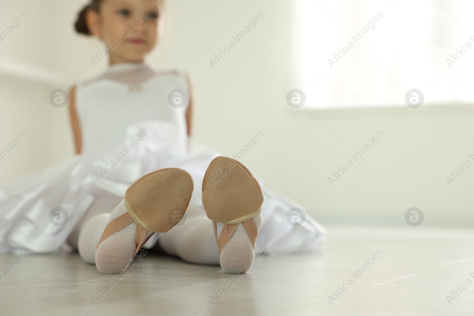 Photo of Little ballerina wearing pointe shoes indoors, selective focus. Space for text