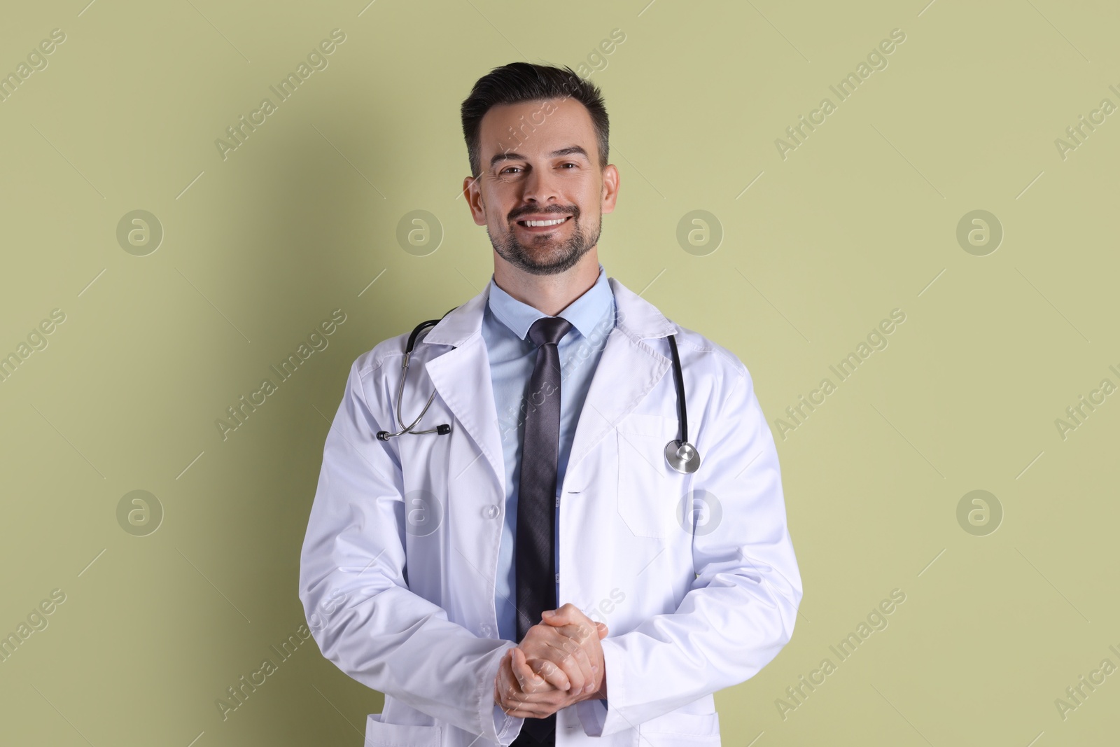 Photo of Smiling doctor with stethoscope on olive background