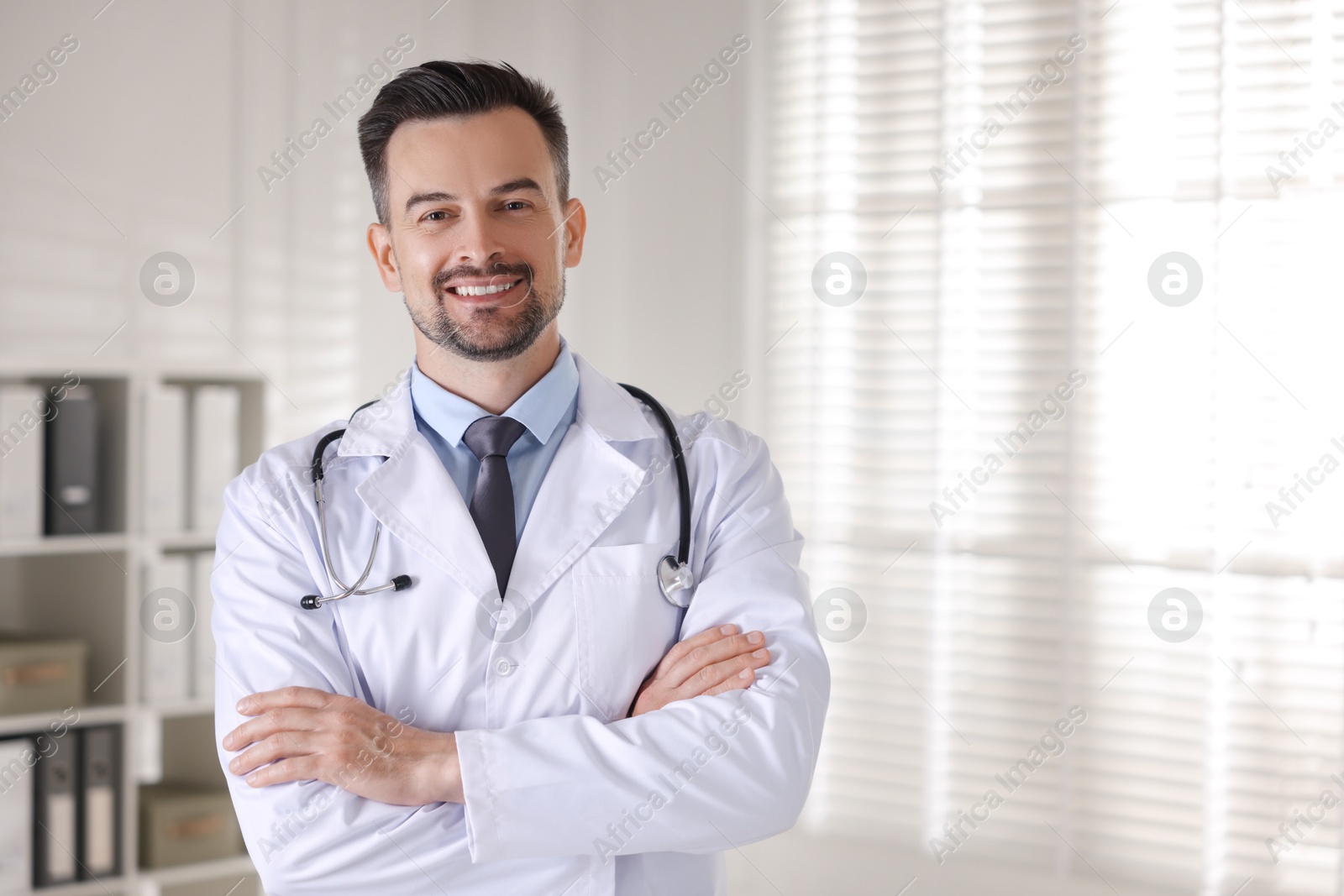 Photo of Smiling doctor with stethoscope in clinic, space for text