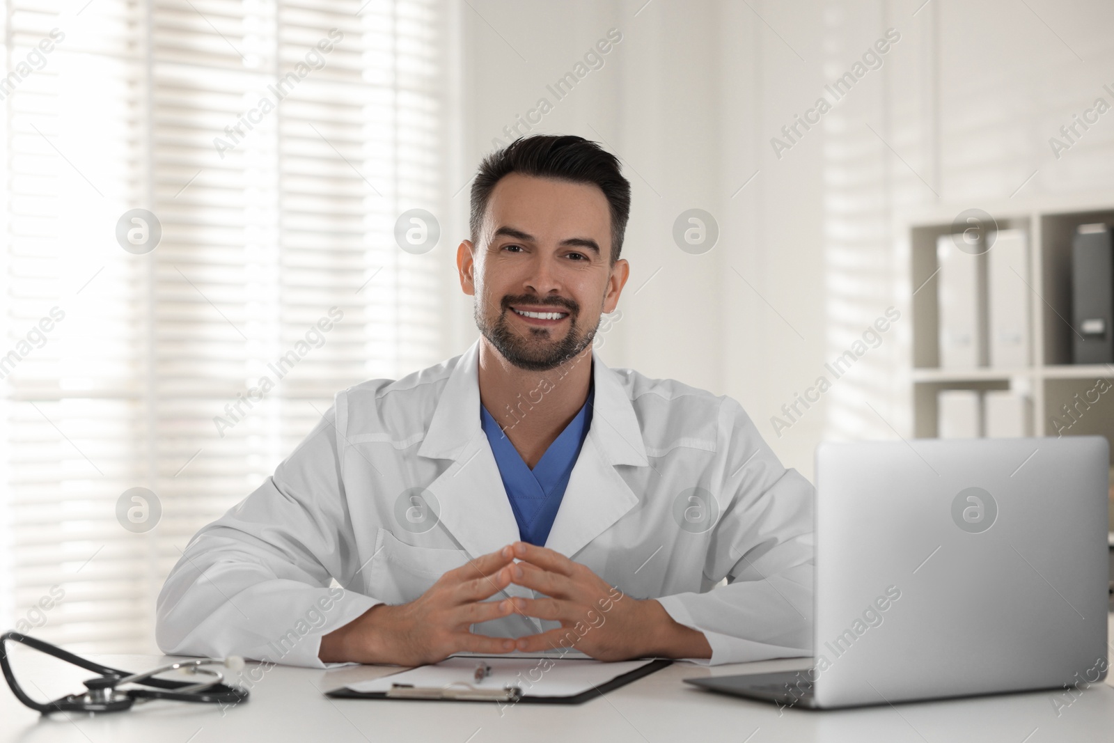 Photo of Smiling doctor working at table in clinic