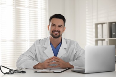 Photo of Smiling doctor working at table in clinic