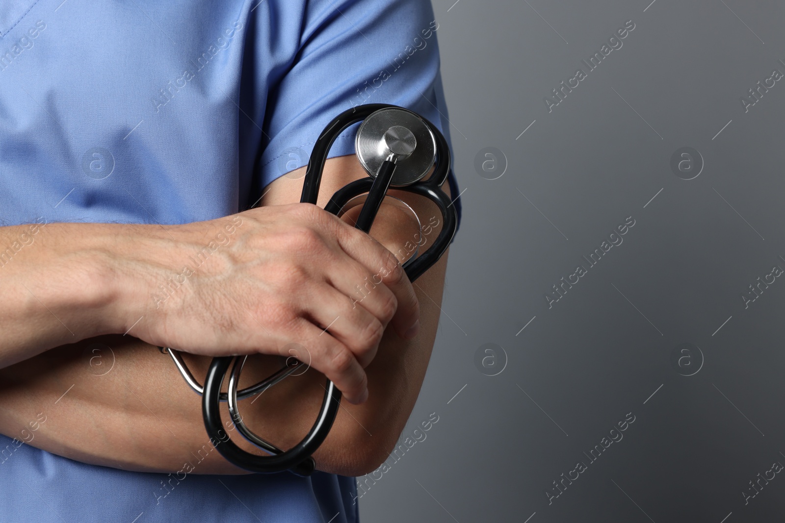 Photo of Nurse with stethoscope on grey background, closeup. Space for text