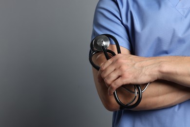 Nurse with stethoscope on grey background, closeup. Space for text