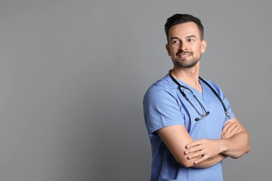 Photo of Smiling nurse with stethoscope on grey background, space for text