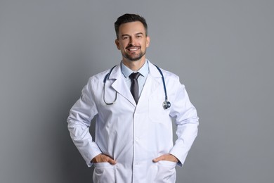 Smiling doctor with stethoscope on grey background