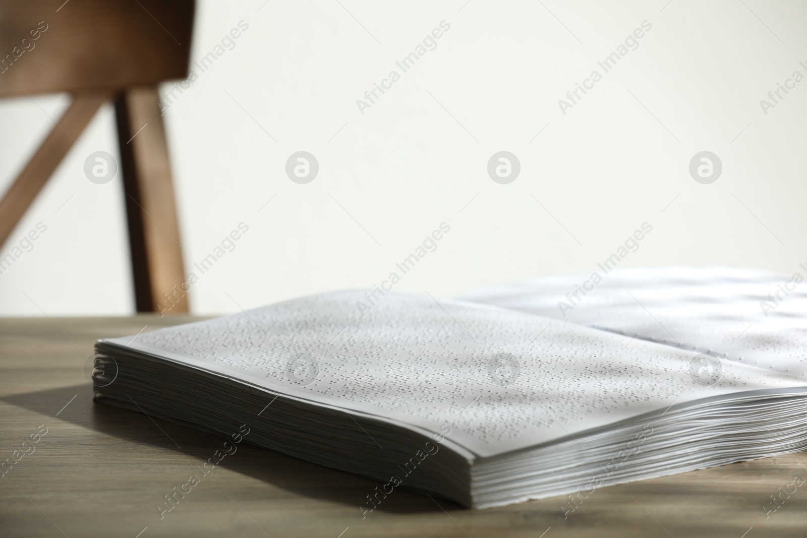 Photo of Book with Braille text on wooden table, closeup. Education and leisure for blind people