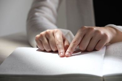 Blind woman reading book written in Braille at table, closeup