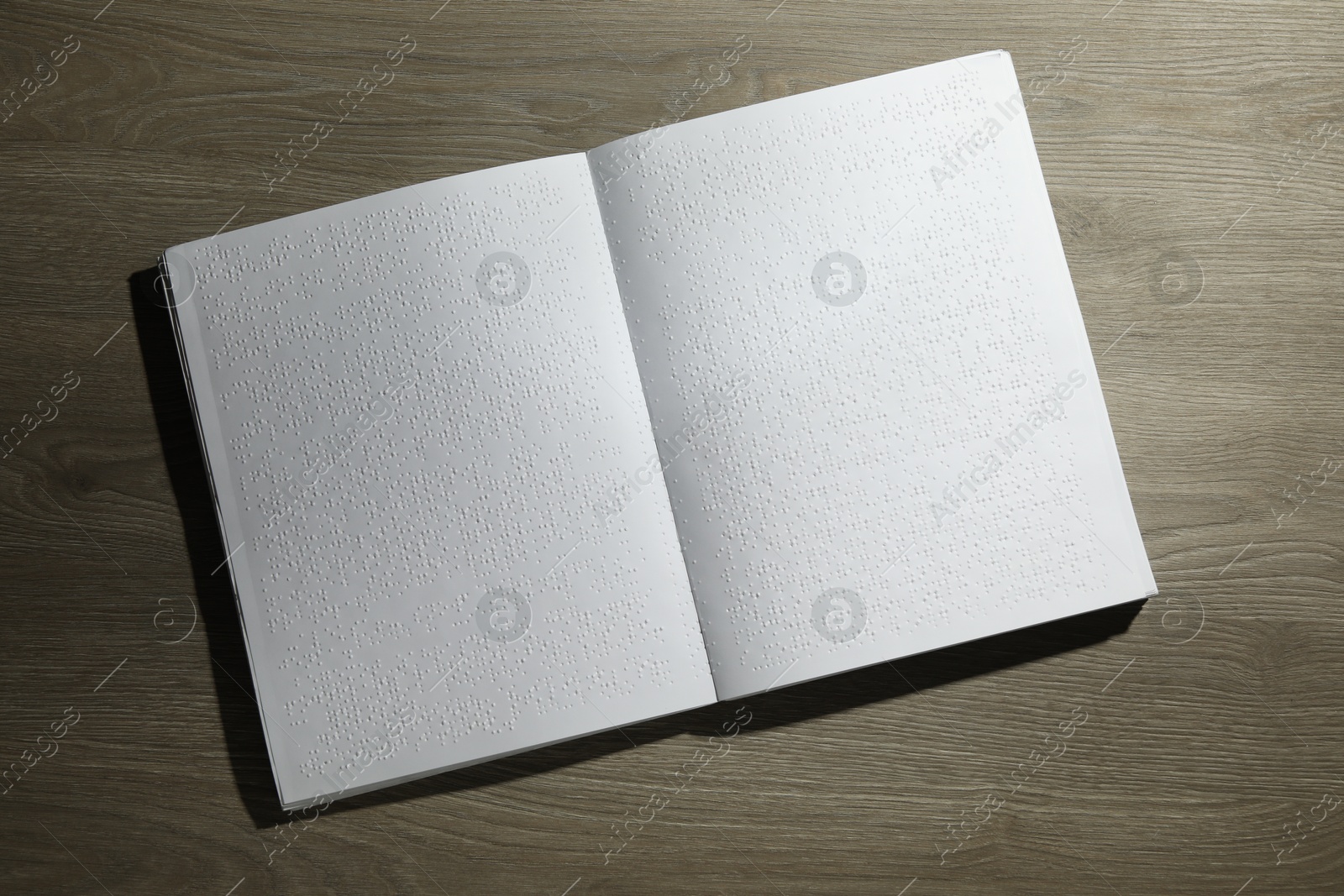 Photo of Book with Braille text on wooden table, top view. Education and leisure for blind people