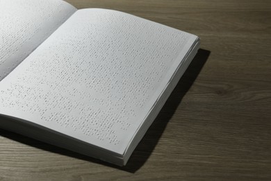 Photo of Book with Braille text on wooden table. Education and leisure for blind people