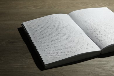 Photo of Book with Braille text on wooden table. Education and leisure for blind people