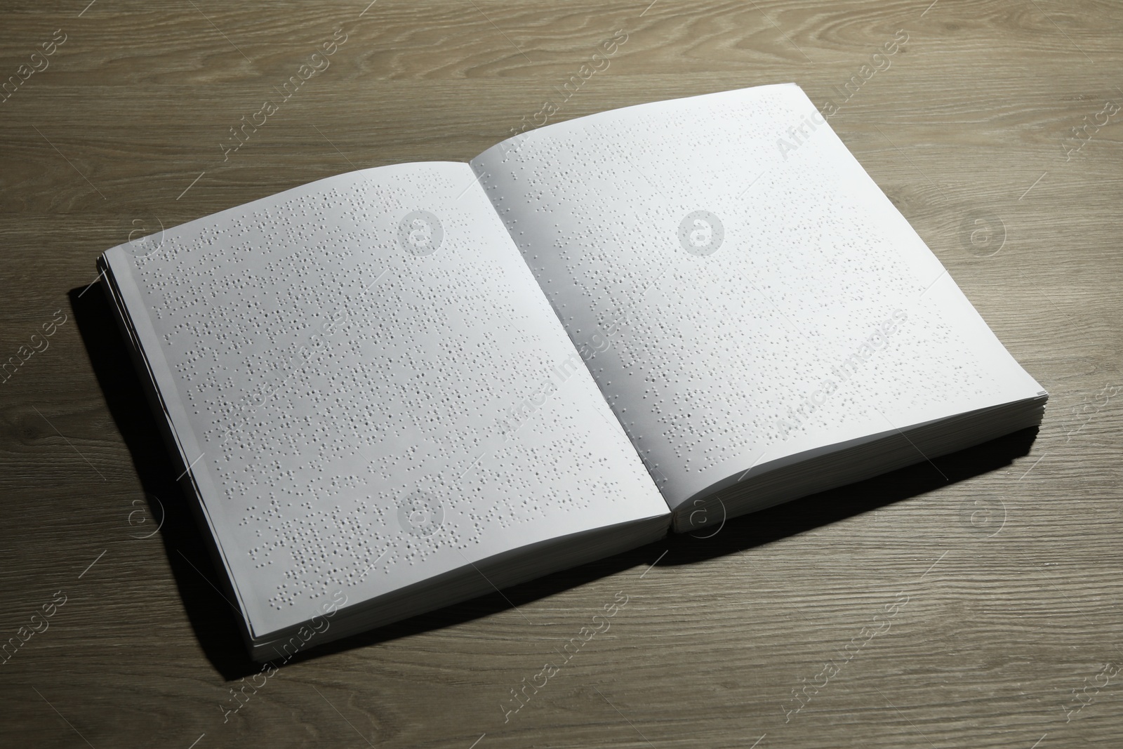 Photo of Book with Braille text on wooden table. Education and leisure for blind people