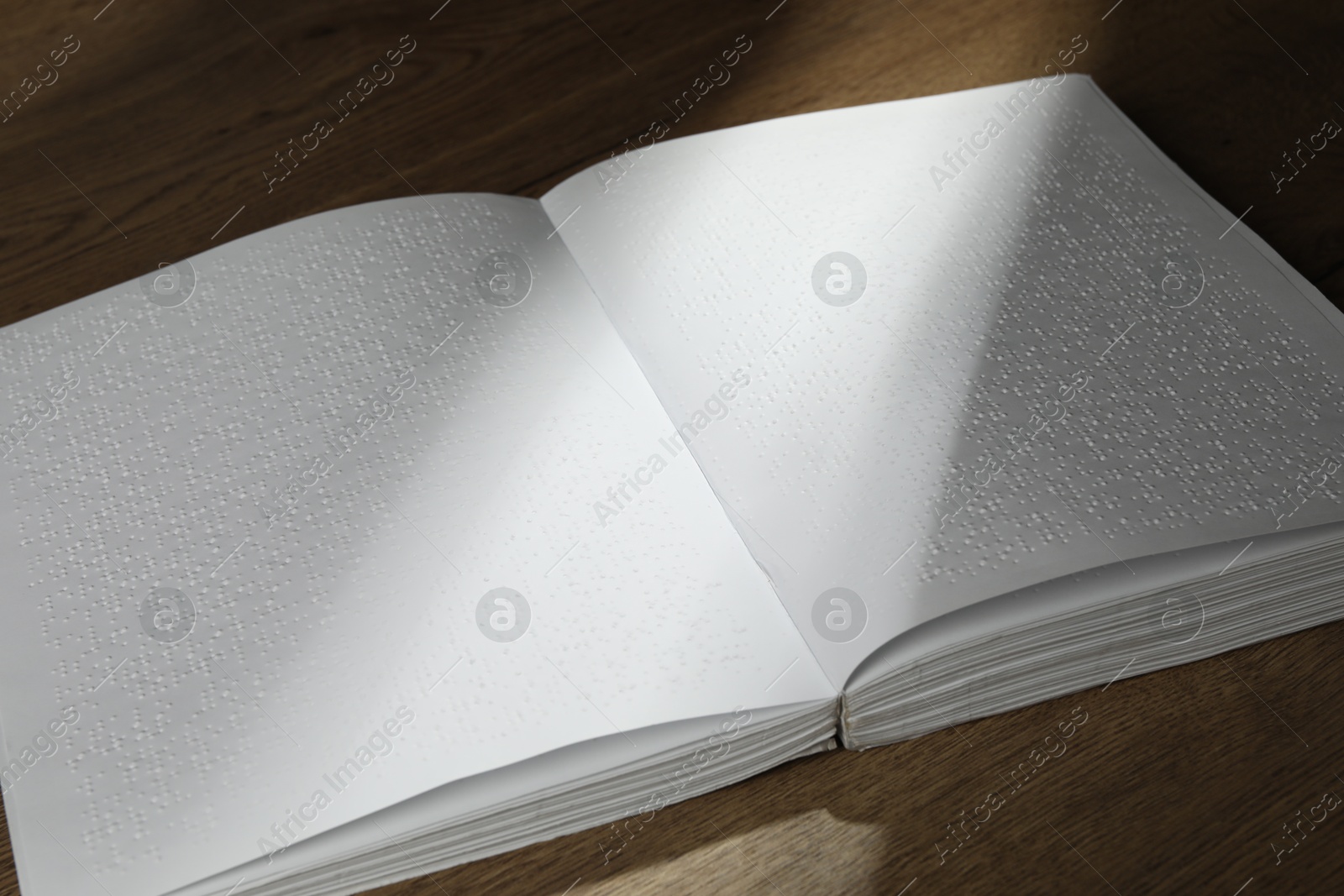 Photo of Book with Braille text on wooden table. Education and leisure for blind people