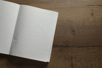 Photo of Book with Braille text on wooden table, top view. Space for text