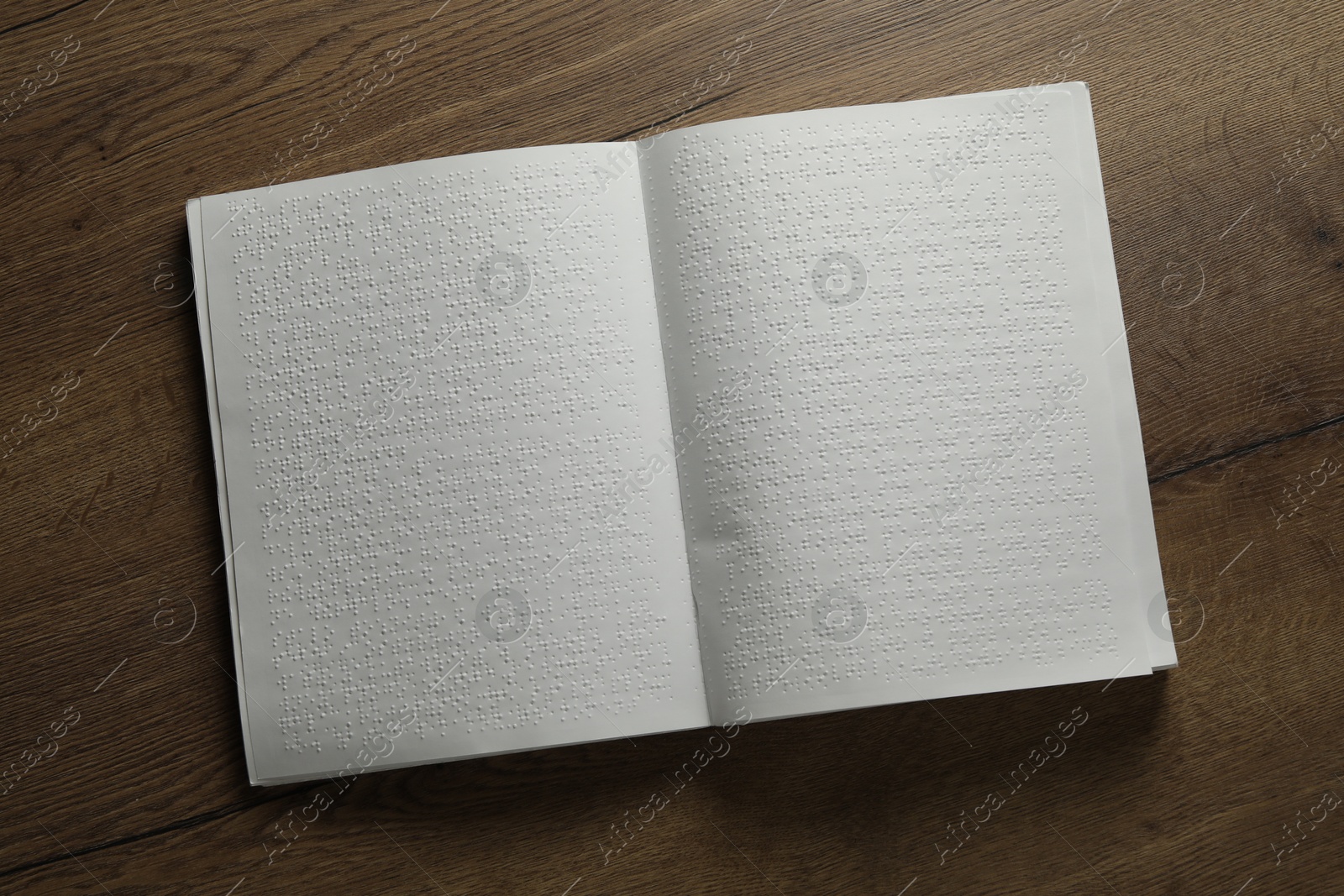 Photo of Book with Braille text on wooden table, top view. Education and leisure for blind people