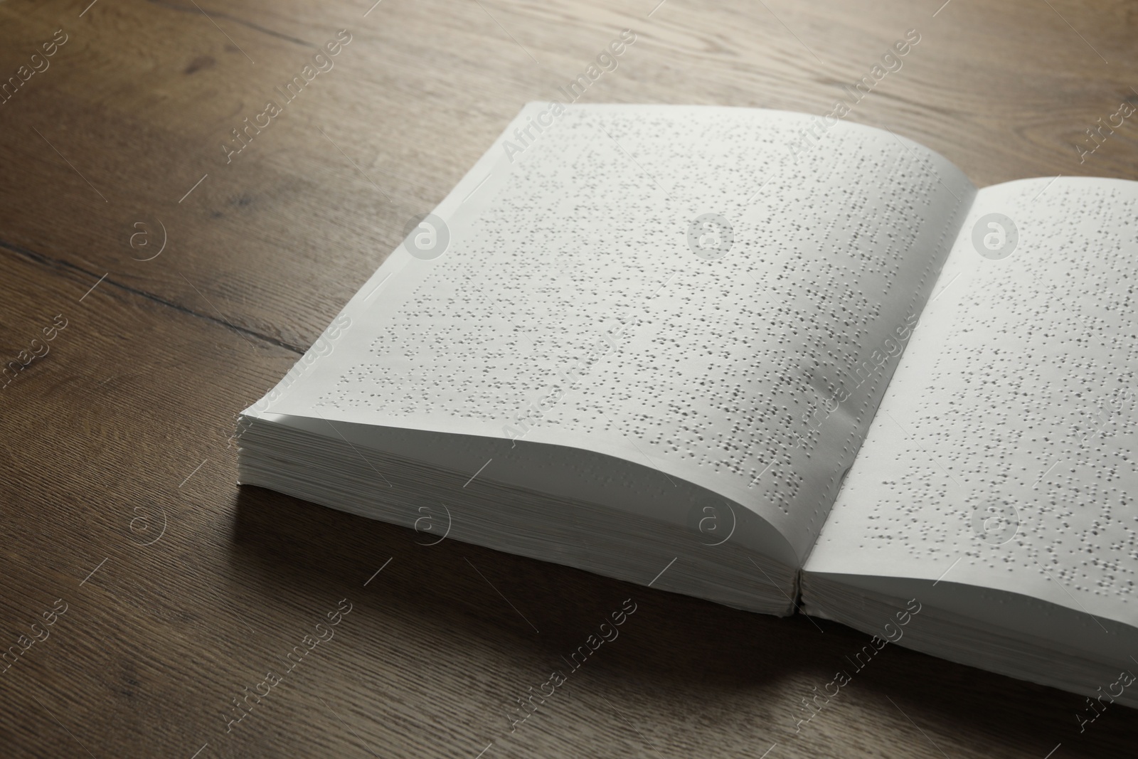 Photo of Book with Braille text on wooden table. Education and leisure for blind people