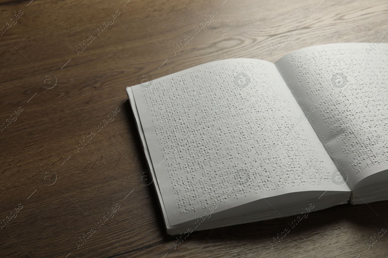 Photo of Book with Braille text on wooden table. Education and leisure for blind people