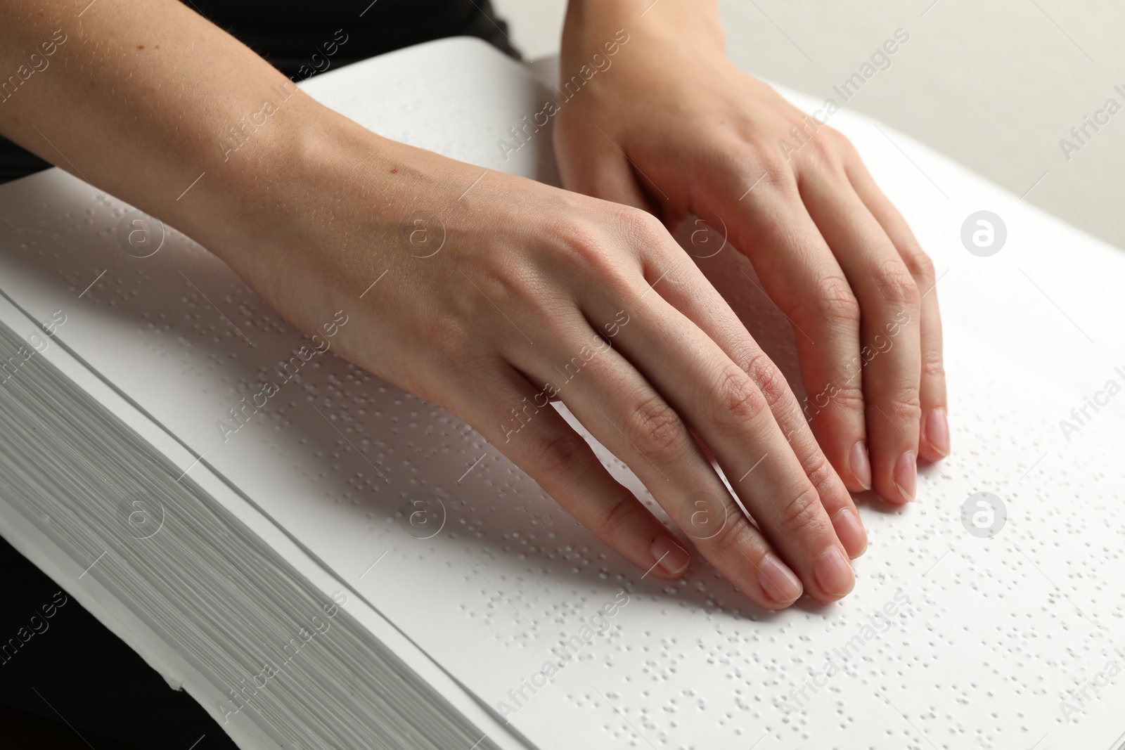 Photo of Blind woman reading book written in Braille indoors, closeup