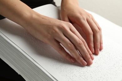 Photo of Blind woman reading book written in Braille indoors, closeup