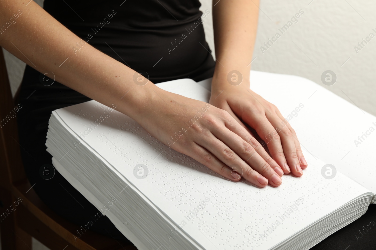 Photo of Blind woman reading book written in Braille indoors, closeup