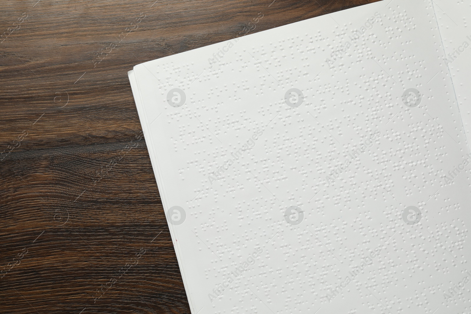 Photo of Book with Braille text on wooden table, top view. Education and leisure for blind people