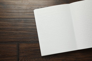 Photo of Book with Braille text on wooden table, top view. Space for text