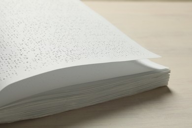 Photo of Book with Braille text on wooden table, closeup. Education and leisure for blind people