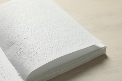 Photo of Book with Braille text on wooden table, closeup. Education and leisure for blind people