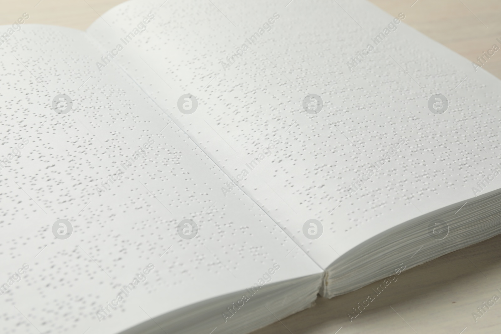 Photo of Book with Braille text on wooden table, closeup. Education and leisure for blind people