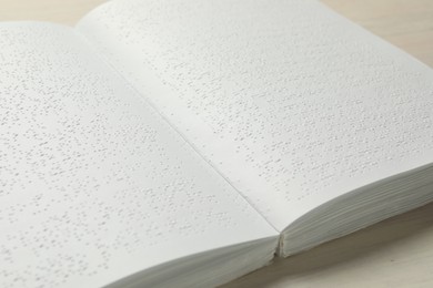 Book with Braille text on wooden table, closeup. Education and leisure for blind people