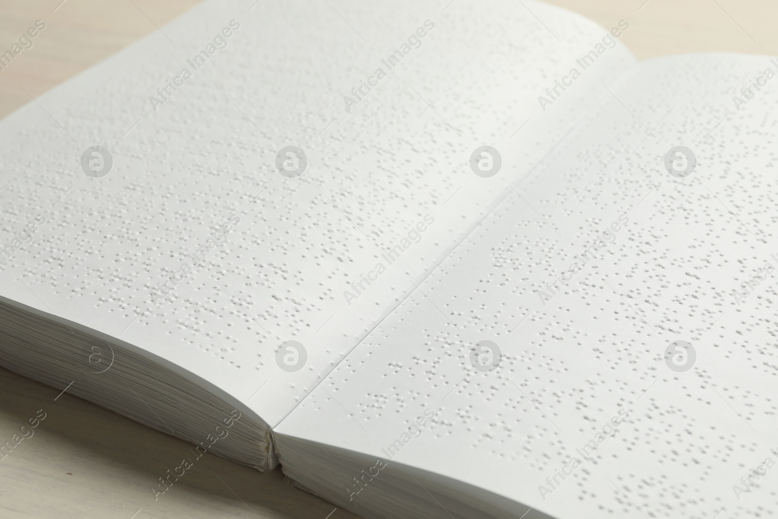 Photo of Book with Braille text on wooden table, closeup. Education and leisure for blind people