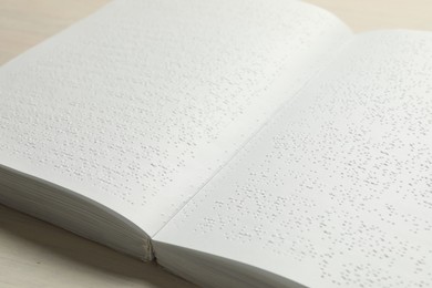 Photo of Book with Braille text on wooden table, closeup. Education and leisure for blind people